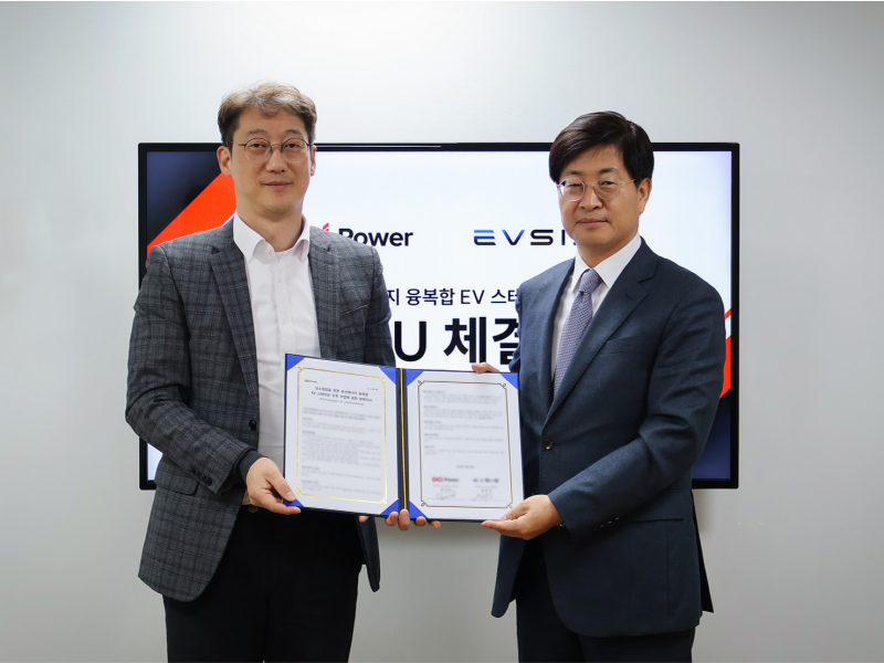 Two men are holding a memorandum of understanding in front of the screen.